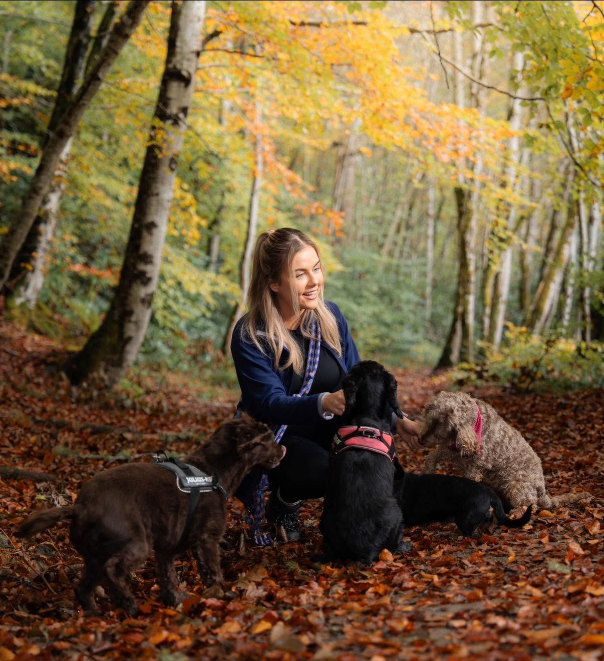 Carly with three dogs in an autumn woodland
